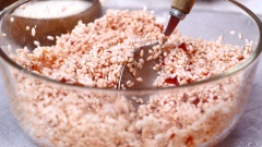 Các bạn cắt đôi trái gấc, nạo lấy 200gr phần ruột gấc bên trong cho vào cái âu nhỏ, thêm 100ml rượu trắng, ngâm 10 phút để thịt gấc lên màu đỏ đẹp và gỡ bỏ hột dễ dàng. Sau đó cho phần nước cốt gấc vào trong tô có 300gr gạo nếp đã ngâm nở 8 tiếng và 1/2 muỗng canh muối. Dùng muỗng trộn đều.