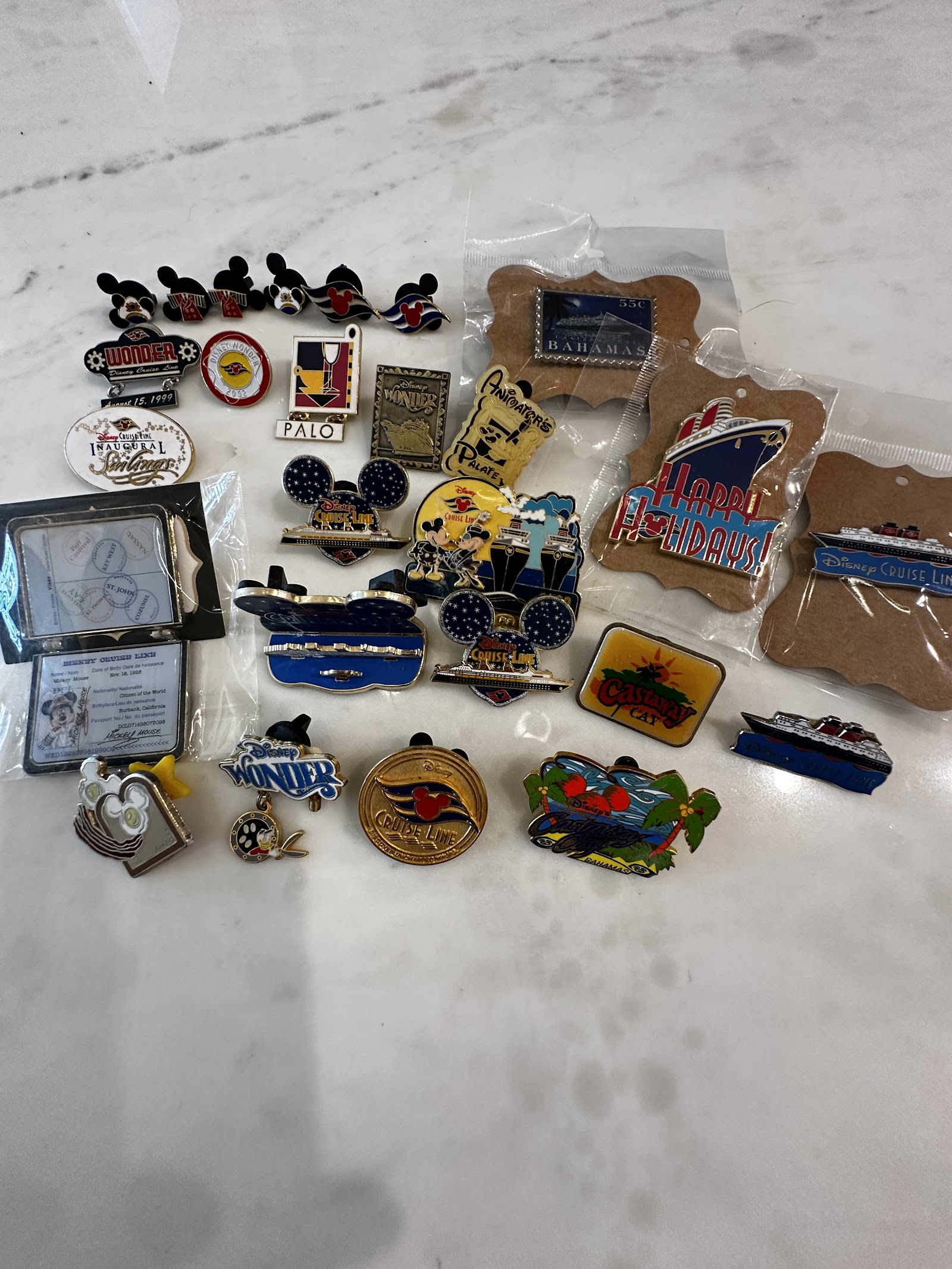 Collection of 22 Disney Cruise Line pins and ephemera from 1998–2005, including sailor-attired character pins, Disney Wonder inaugural voyage commemorative pin, Castaway Cay scene pin, and restaurant pins for Palo and Animator's Palate, most in original packaging