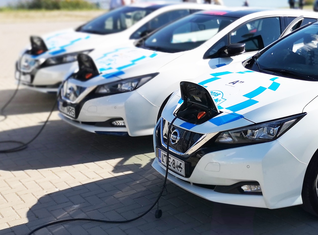 White Electric Vehicles Charging at a Charging Station from the Front Trunk on a sunny day as example of green inflation