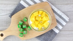 Lấy một ly lớn, lần lượt bỏ từng tầng nguyên liệu vào: milo cube, kem whipping - xoài - socola vụn.