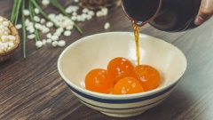 Đầu tiên các bạn sơ chế trứng muối nhen. Trứng muối mua về rửa sạch lớp rơm đen, tách lấy lòng đỏ trứng, rửa sạch dưới nước nhẹ để loại bỏ hết lòng trắng. Cho thêm rượu mai quế lộ (có thể thay bằng rượu gừng tự ngâm), ngâm trong 10 phút. Rửa thật sạch.