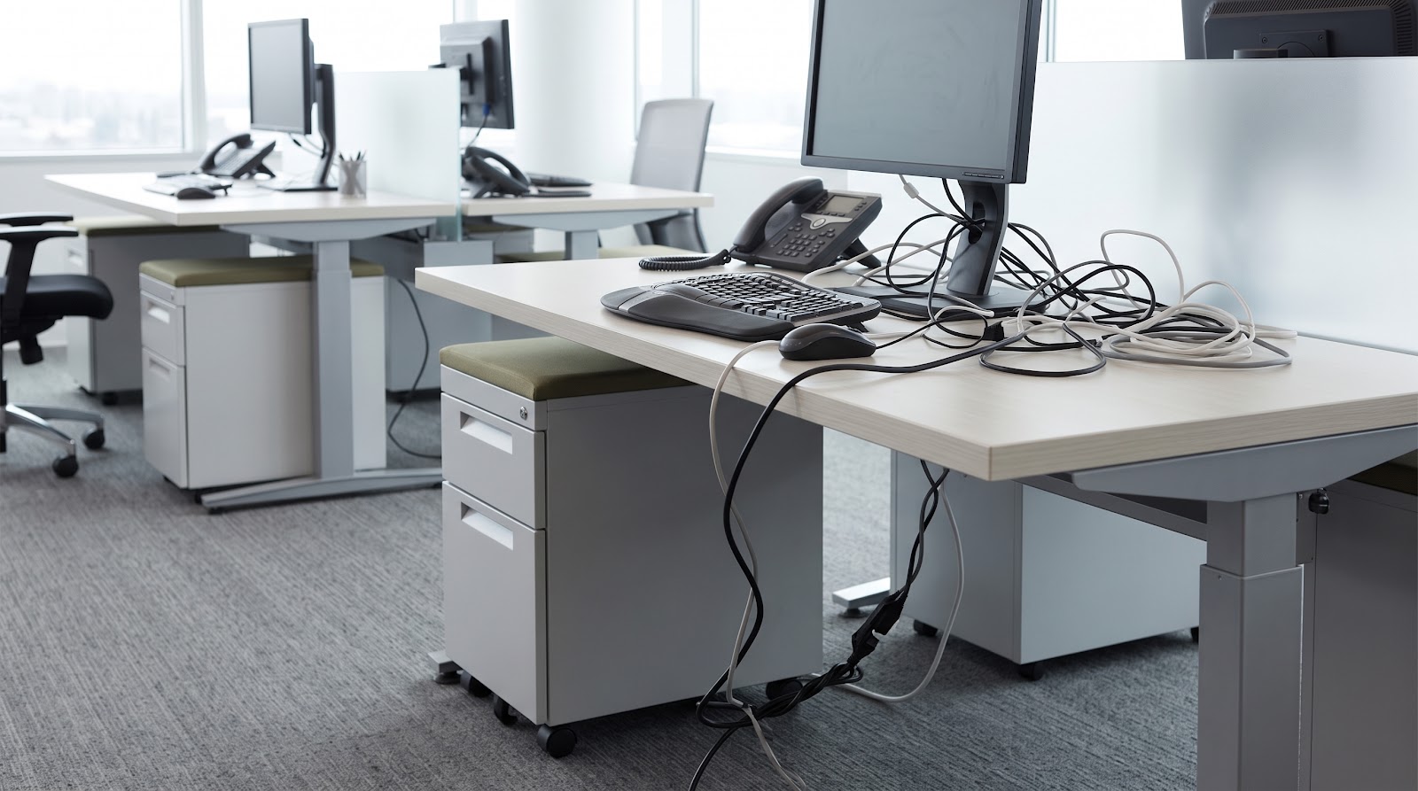 Kabel stopkontak komputer berserakan di bawah meja kerja kantor
