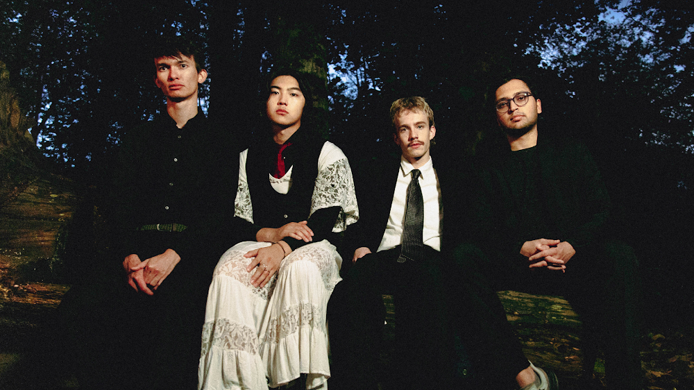 The jazzy emo band Tiger Really, sitting on a big log in a park in the evening. 