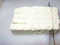 Cắt phô mai feta thành những lát chéo, mỏng, tiếp tục cắt chúng ra thành những miếng nhỏ.