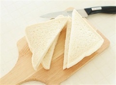 Bánh mì cắt bỏ phần viền rồi cắt chéo góc bánh làm đôi.