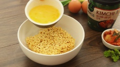 Xếp lần lượt mì gói, gia vị mì, 1 quả trứng gà đánh tan, 10gr đầu hành lá và 80gr kim chi Bibigo vào tô. Chế khoảng 300ml nước sôi vào tô rồi đậy nắp lại.