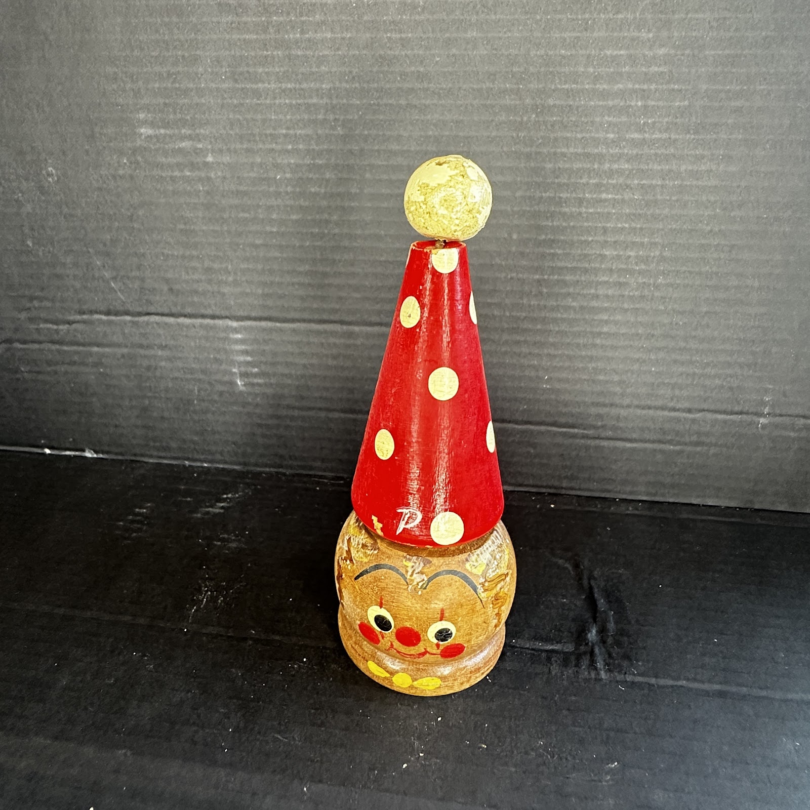 Vintage turned wood Pinocchio stacking toy with red conical hat, yellow pom-pom topper, and hand-painted facial details, circa 1940s–1960s