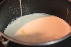 Cho tiếp sữa chua vào nồi sữa tươi, dùng muôi khuấy đều để hỗn hợp sữa chua tan hoàn toàn. Tiếp tục cho bát gelatine vào nồi sữa, khuấy đều để hỗn hợp gelatine tan, bạn có thể lọc lại qua rây để bỏ bớt lợn cợn, bạn thử lại độ ngọt vừa ý, nếu nhạt thì thêm vào một ít sữa đặc.