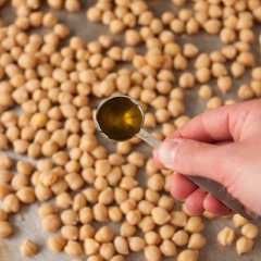 Rưới đều dầu olive. Cho đậu và vào lò nướng trong 20-30 phút, cứ 10 phút lấy ra lắc đều khay đậu gà rồi trải lại 1 lần cho đậu gà được vàng đều. Cuối cùng lấy đậu ra rắc muối và bột ớt lên, xóc đều một lần nữa cho gia vị bám đều xung quanh đậu.