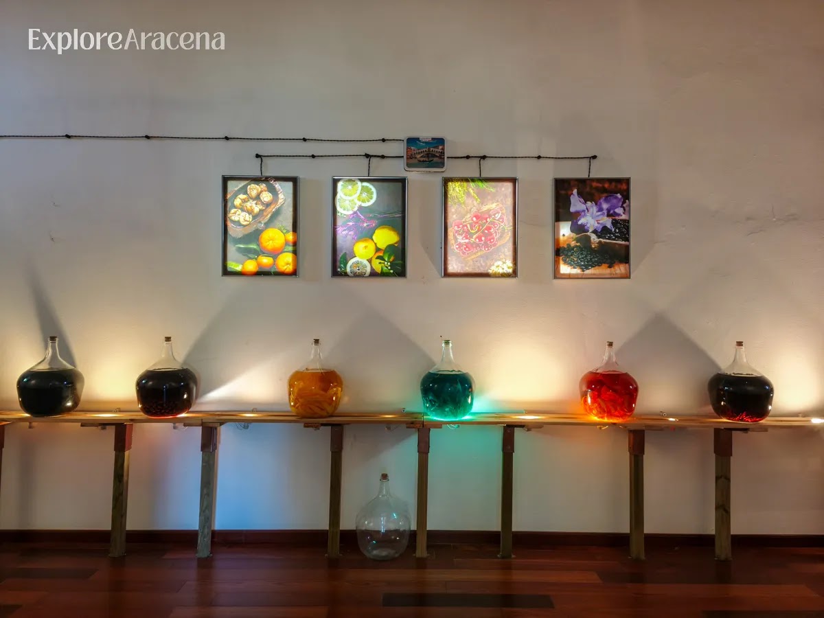 A display of colourful liqueur bottles framed by an arched doorway inside the Martes Santo distillery museum near Aracena.