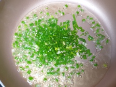 Làm nóng dầu, cho hành lá cắt nhỏ vào phi thơm cùng 15gr xốt nêm rồi cho nghêu đã hấp vào xào chung. Thịt nghêu áo đều xốt mỡ hành thì tắt bếp.