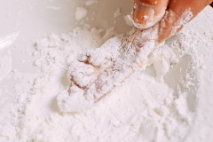 Cho thịt gà vào dầu mè, hạt tiêu, bột tỏi, muối, rượu rồi trộn đều. Ướp thịt gà trong 30 phút. Sau đó cho thịt gà lăn vào đĩa bột bắp. Làm nóng dầu hạt cải trong chảo nhỏ cho đến khi được khoảng 350 độ F (khoảng 180 độ C). Sau đó cho thịt gà vào chiên cho đến khi vàng. Cho thịt gà ra đĩa.