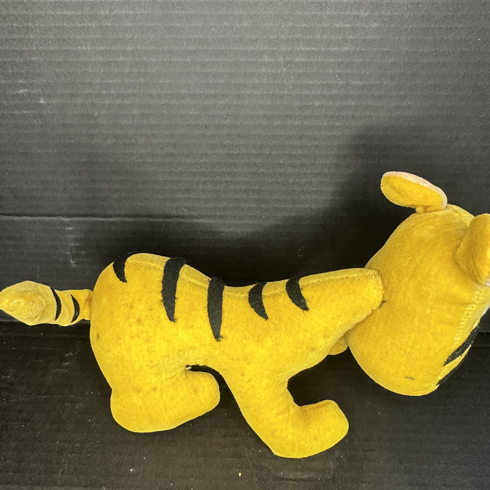 Small vintage velvet Tigger stuffed figure from the 1960s with head in a gentle slump, orange and black fabric showing age-appropriate patina