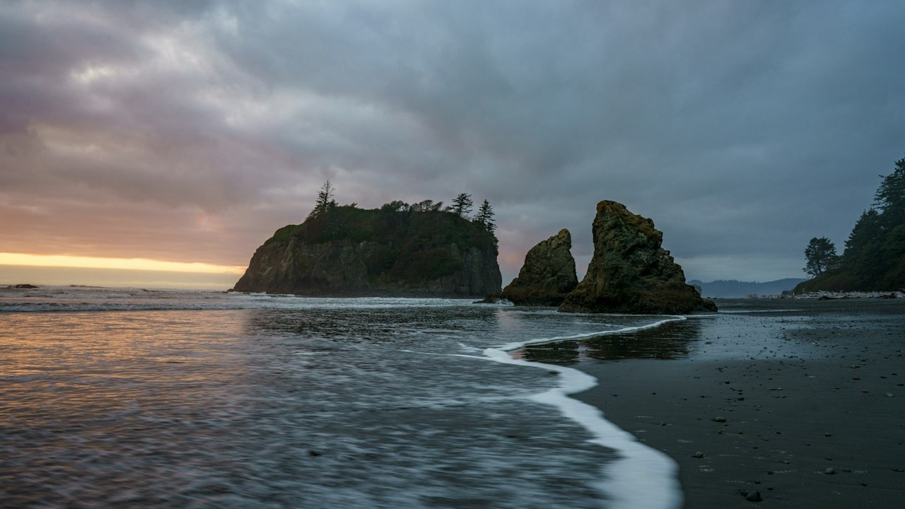Iconic Abbey Island sea stacks and Pacific surf rolling onto the dark sand of Ruby Beach on the Olympic Peninsula
