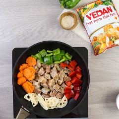 Bắc chảo lên bếp, dầu nóng cho 10gr tỏi băm và 10gr gừng băm vào phi vàng. Vặn lửa lớn, tiếp tục thêm gân bò, củ sen, cà rốt và ớt chuông vào, đảo đều 2 phút.