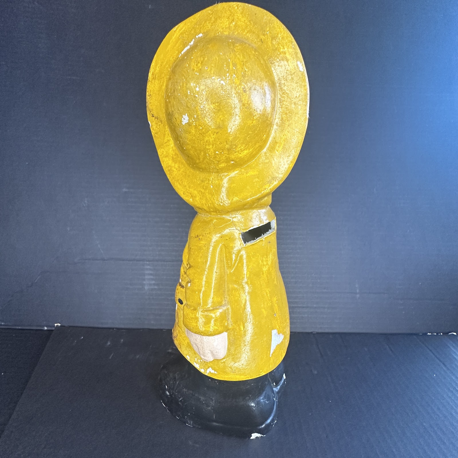 Ceramic Donald Duck coin bank wearing yellow raincoat and hat with black boots, approximately 10-12 inches tall, showing age-related paint wear and glossy finish