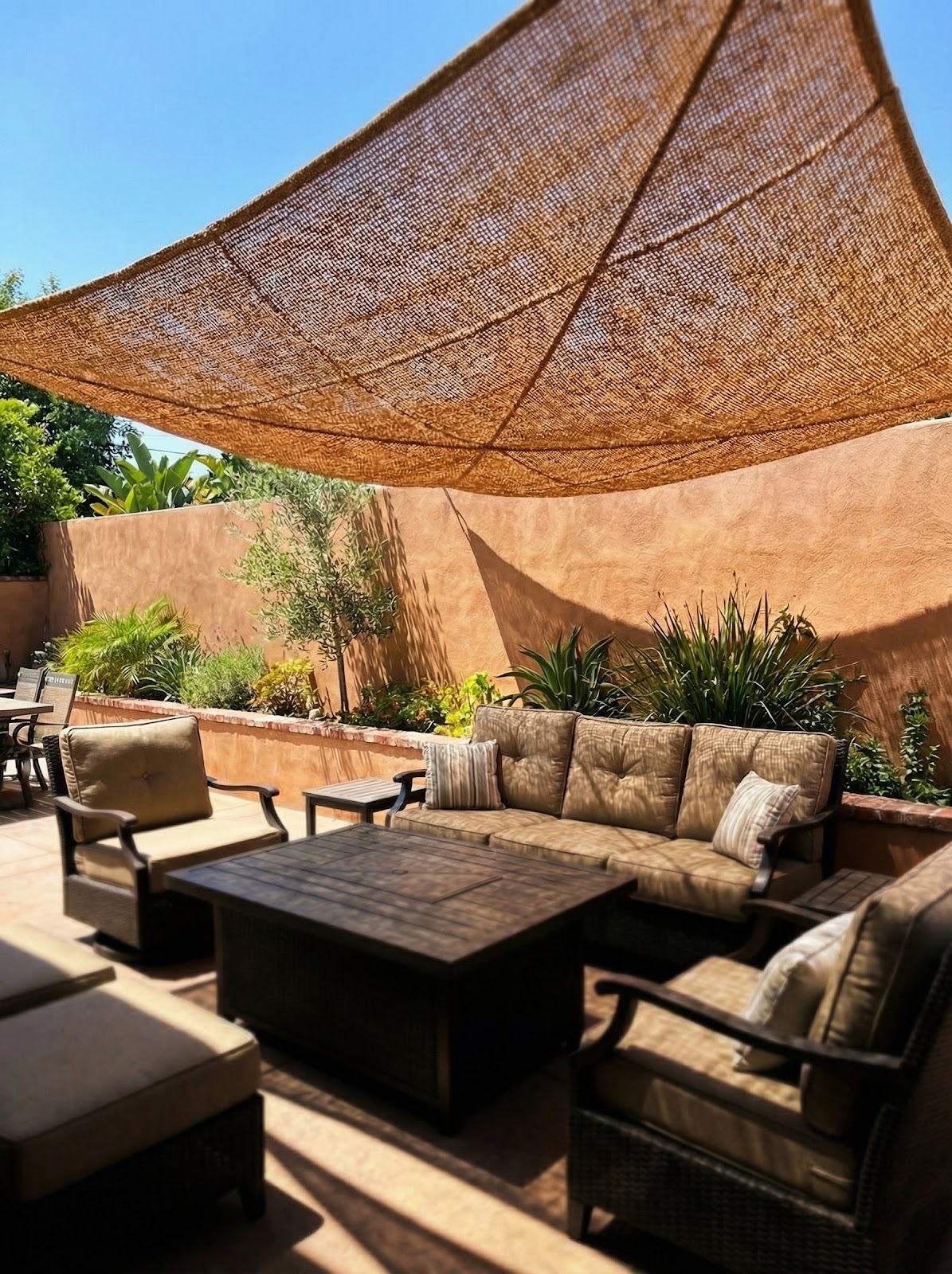 Layered natural coir shade sail over outdoor lounge seating