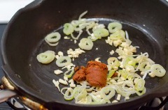 Thêm 2 muỗng cà phê dầu, phi thơm hành boa rô thái nhỏ và tỏi băm. Thêm cà ri vào và trộn cà ri với hành tỏi cho đến khi thơm. Thêm 1 muỗng cà phê dầu và cho cơm vào. Sử dụng muỗng để đánh cơm cho tơi ra. Đảo cơm cho đến khi trộn đều hoàn toàn với cà ri.
