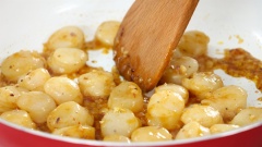 Bắc chảo nóng, thêm vào 2 muỗng canh dầu ăn, cho 10gr hành tím băm và 10gr tỏi băm vào phi thơm. Sau đó thêm cồi sò điệp đã ướp vào xào sơ 2 phút cho cồi sò săn lại thì trút ra dĩa để riêng.