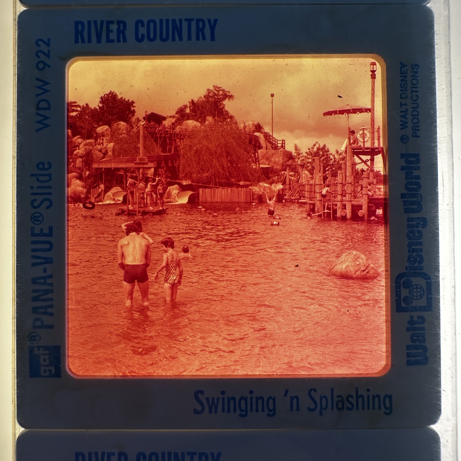 1976 GAF Pana-Vue 35mm slide in cardboard mount showing the Boom Swing rope swing area at River Country, Walt Disney World, with warm red color shift characteristic of the era