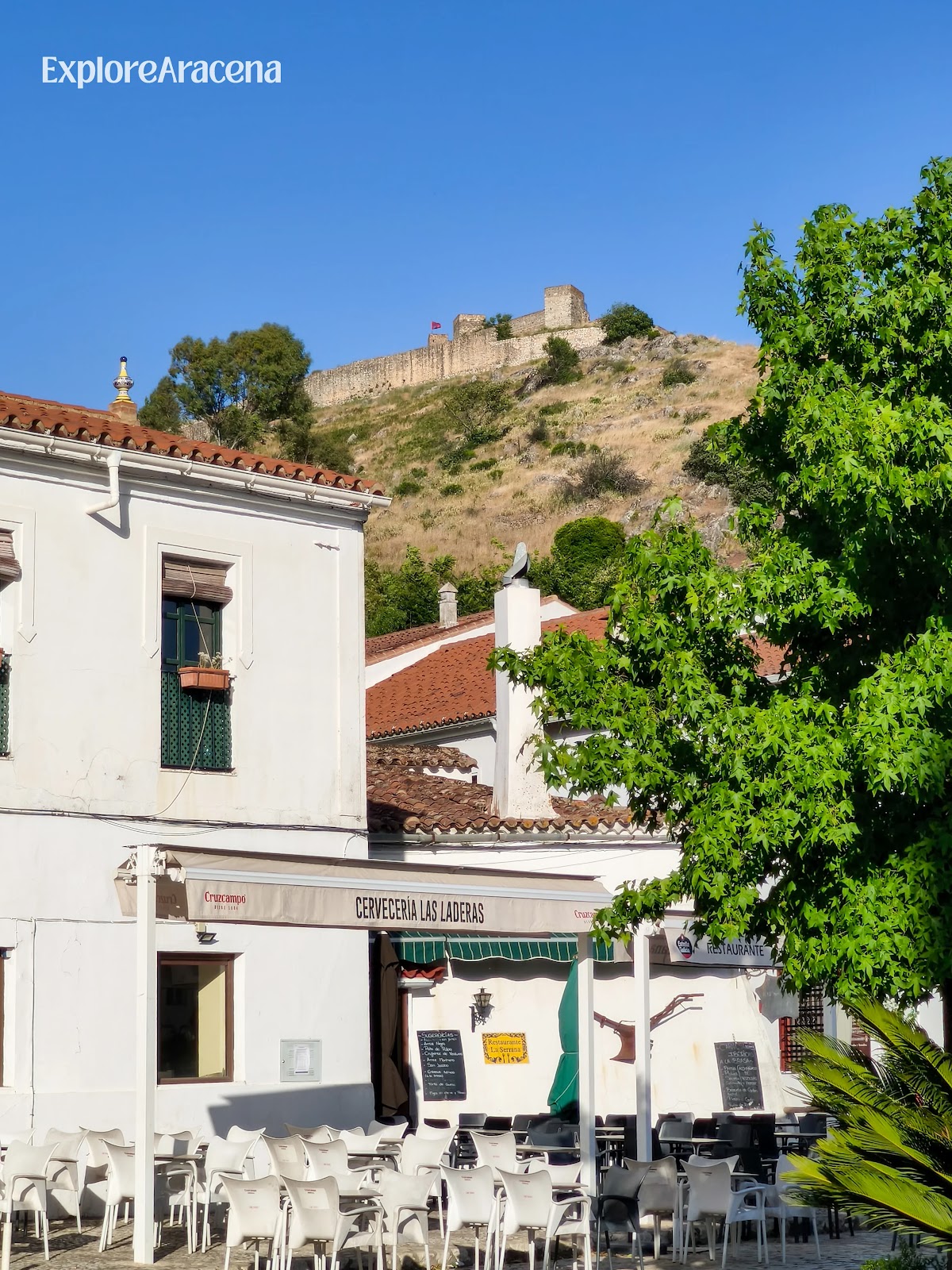 Outdoor bar terrace in Aracena with tables beneath the castle overlooking the town.