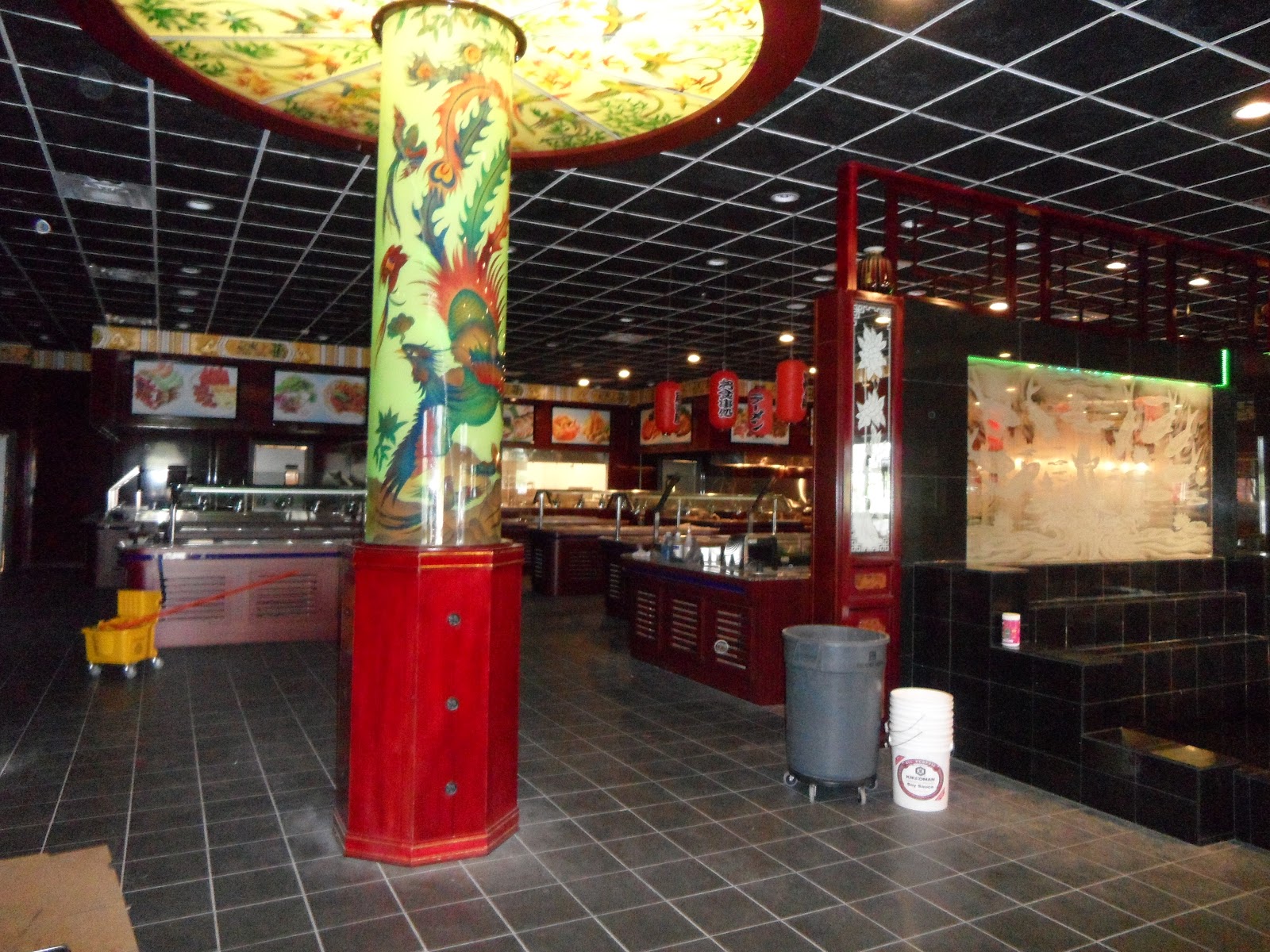 Interior view with buffet stations, red lanterns, and a prominent decorative column with green and yellow designs.
