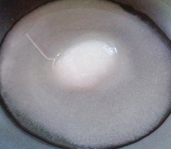Cho 130gr đường cùng 700ml nước lạnh vào chảo nấu tan đường với lửa nhỏ. Cho thau cùi bưởi vào sên đều cho đến khi đường thấm hết vào cùi bưởi và khô thì tắt bếp.