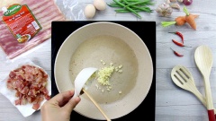 Trên chảo lúc nãy chiên thịt xông khói, bạn cho tỏi băm vào phi vàng thơm. Sau đó cho cà rốt, đậu que và kim chi vào, xào cho các loại rau củ vừa chín tới.