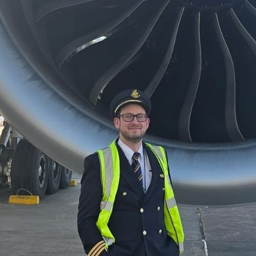Dean Hardman, cofondateur et instructeur d'INRAT Exam Prep, en uniforme devant un réacteur d'avion