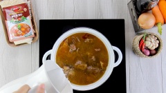 Bắc nồi, làm nóng 2 muỗng canh dầu ăn, cho hành tím và tỏi vào phi vàng thơm. Tiếp tục cho thịt bò đã ướp vào xào đều tay, đến khi thịt bò săn lại thì chế vào nồi 1 lít nước. Đầu tiên đun lửa lớn cho nước hầm sôi lên, vớt bỏ bọt cặn đi rồi hạ nhỏ lửa hầm 1 tiếng cho thịt bò mềm.