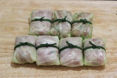 Dùng cọng hành lá đã trần sơ để buộc miếng bắp cải cuộn thịt lại. Chỗ thịt xay còn thừa bạn vo viên lại thành từng viên tròn nhỏ.