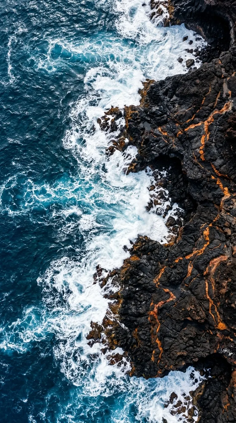 Vertical Aerial View of Black Volcanic Rock Meeting Deep Blue Ocean - Free 4K mobile Wallpaper