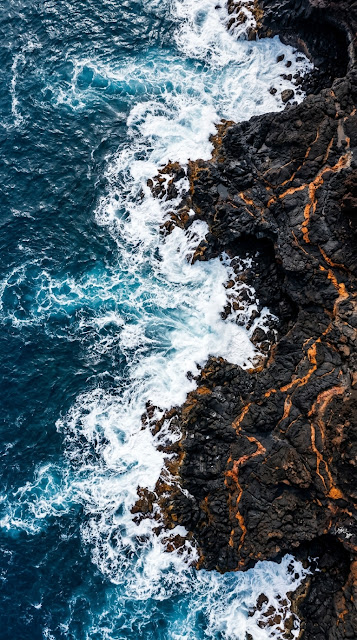 Vertical Aerial View of Black Volcanic Rock Meeting Deep Blue Ocean - Free mobile Wallpaper
