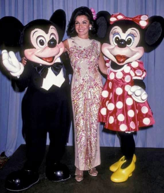 Professional Mickey Mouse and Minnie Mouse mascot costume set from late 1980s Disney Character Programs, showing large-eye mask molds and Minnie's flower hat and polka-dot dress