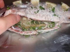 Thoa sốt mayonnaise đều khắp mình cá. Hành tây thánh sợi nhỏ theo chiều ngang. Đun nóng dầu ăn trong chảo, cho hành tây vào đảo đều cho mềm và thơm, tắt bếp. Tỏi thái lát nhồi vào bụng cá cùng với hành tây, ngò rí. đặt vài lát chanh lên thân cá. Xếp cá vào giấy bạc, gói kín lại.