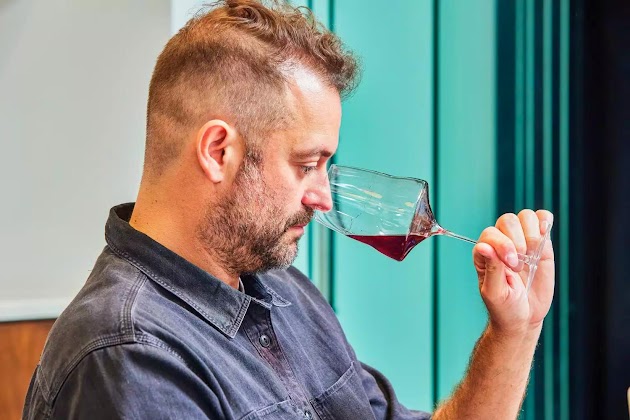 Una persona oliendo vino tinto de una Josephine No 2 – Universal Glass
