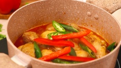 Khi nồi gà sôi nêm gia vị với 2 muỗng canh nước mắm, 1 muỗng canh hạt nêm, 1 muỗng canh đường. Đảo đều cho gà thấm gia vị. Om gà 20 phút đến khi thịt gà chín mềm, nước hơi sánh thì cho ớt xanh và ớt chuông đỏ vào nồi. Om thêm 5 phút rồi tắt bếp.