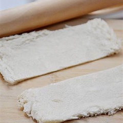 Bánh mì cắt bỏ các cạnh cứng, cán mỏng rồi cắt mỗi lát làm đôi.