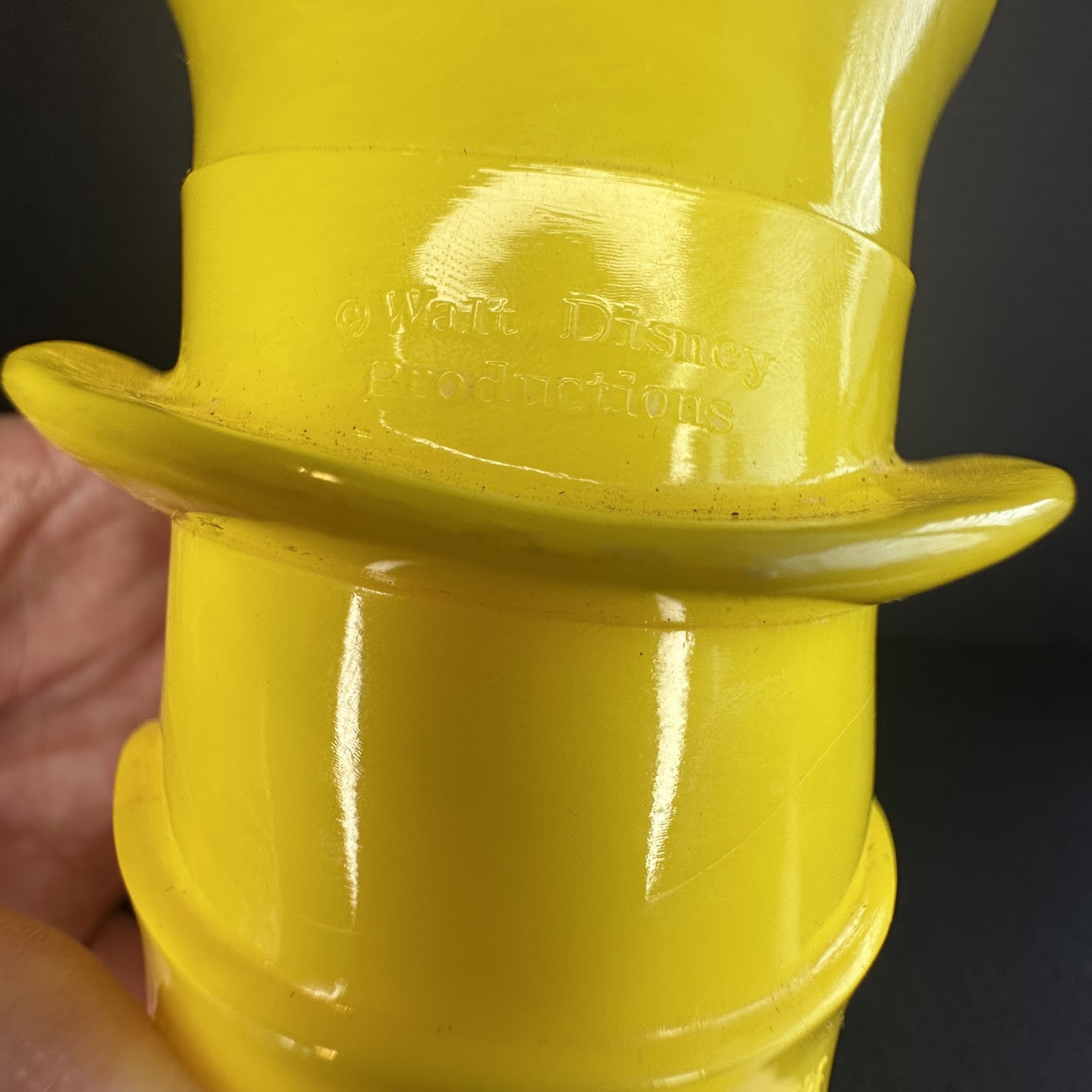 Vintage yellow molded plastic Winnie the Pooh character piece with glossy finish and embossed Walt Disney Productions copyright mark on reverse, circa 1970s–1980s