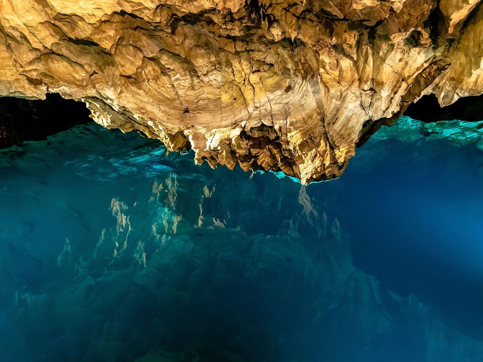Still underground lake inside the Gruta de las Maravillas reflecting rock formations in crystal-clear water.