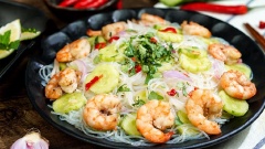 Đổ miến đã luộc vào âu dưa leo trộn đều. Sau đó cho miến đã trộn ra đĩa, thêm tôm đã chiên và rắc chút ngò rí thái nhỏ lên trên là xong.