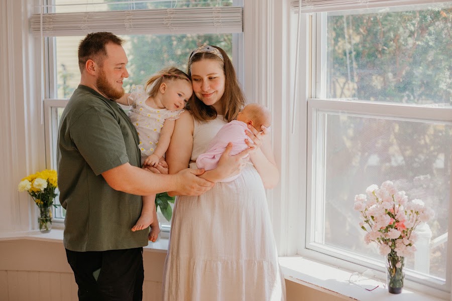 Family portrait with children and newborn in warm window light — Eastern CT