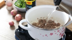 Bắc nồi, cho vào 1 muỗng canh dầu ăn rồi đun nóng. Thêm hành tím vào phi thơm rồi cho thịt bò băm vào xào vừa tái. Nêm vào thịt bò 1 muỗng canh nước mắm, 1/2 muỗng canh đường rồi xào cho thịt bò ngấm gia vị. Chế vào nồi 800ml nước sôi.