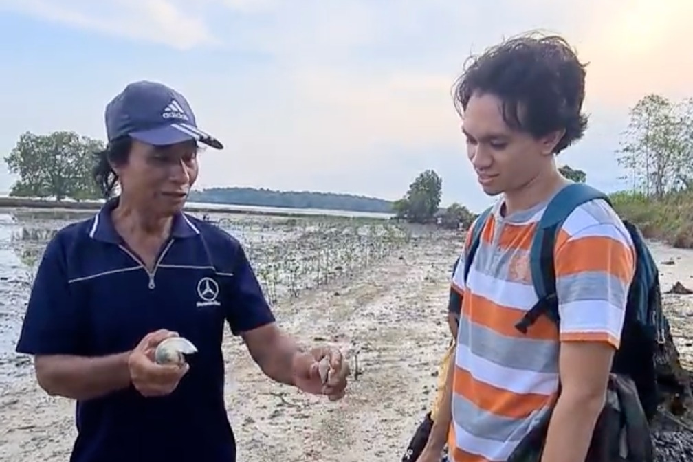 Our mangrove farmer showing biodiversities found around  the conservation area