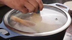 Cho nồi lên bếp, châm vào nồi 2 lít nước để nấu nước dùng, cho xương gà vào ninh nhỏ lửa đậy nắp hé hớt bọt thường xuyên. Sau khi ninh xương được 1 tiếng cho hạt mùi,quế thanh, hoa hồi vào túi gia vị, bỏ vào nồi nước dùng cùng với gừng, gốc ngò rí,hành tím và hành tây đã nướng. Sau 20 phút cho gà vào luộc để nhỏ lửa. (hầm xương và rau củ một thời gian trước khi cho gà vào luộc sẽ làm cho nước dùng ngấm vào gà, thịt được đậm đà thơm ngon hơn)