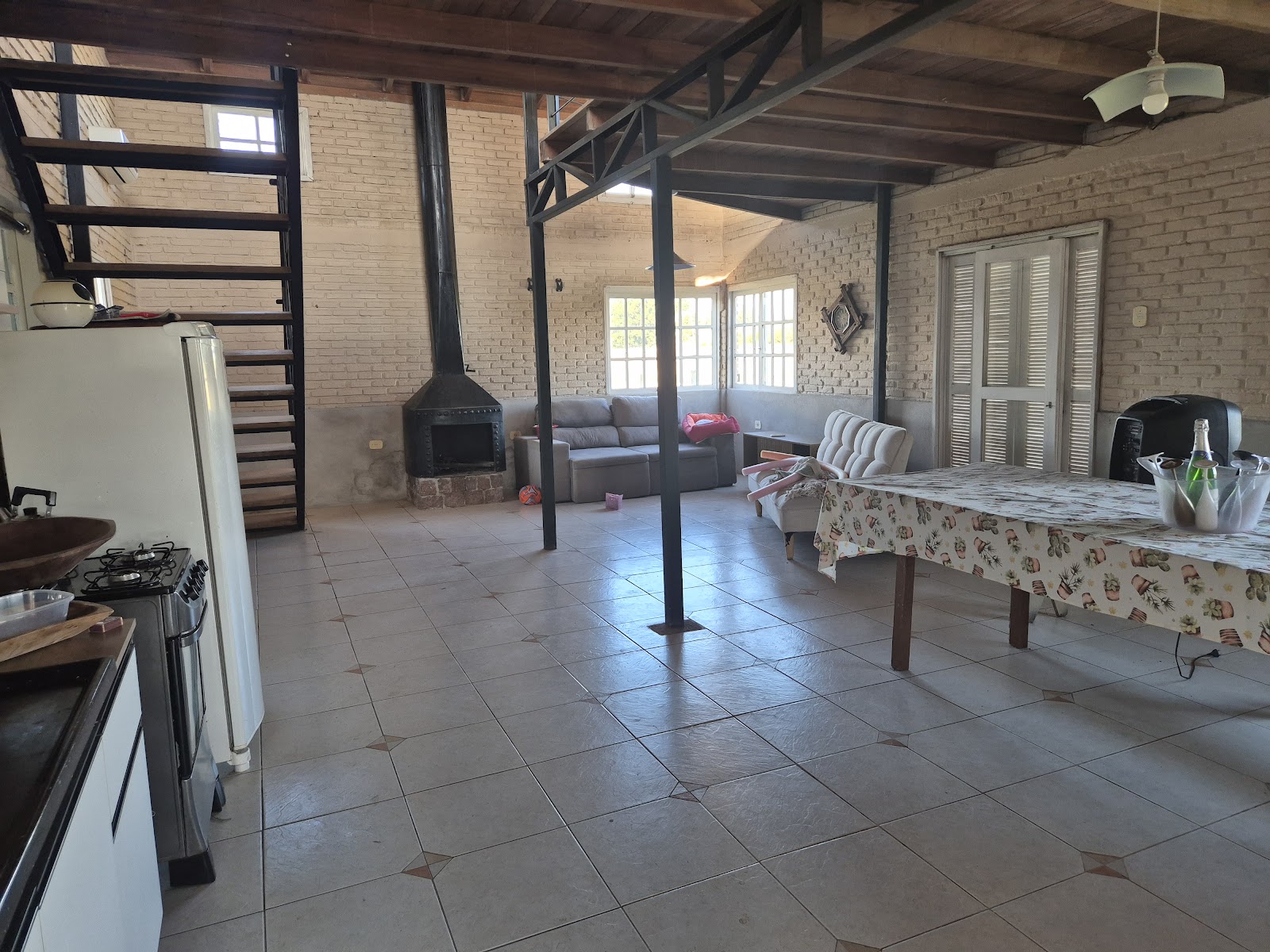 Interior da casa principal com lareira e teto de madeira