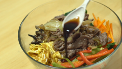 Trước khi trộn, cho miến vào tô lớn, thêm 1 muỗng canh nước tương, 1 muỗng cà phê dầu mè trộn đều. Cuối cùng, lần lượt cho cà rốt, ớt chuông, cải bó xôi, trứng chiên, thịt bò và hành tây đã chế biến vào, nêm 2 muỗng canh nước tương, 2 muỗng cà phê đường, 2 muỗng tỏi băm, 2 muỗng cà phê dầu mè, 1 muỗng cà phê mè rang. Trộn thật đều các nguyên liệu lại với nhau.