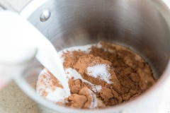 Cho đường, bột cacao, muối và lượng sữa tươi còn lại vào một cái tô khác. Dùng phới trộn đều. Rót hỗn hợp này vào nồi nhỏ rồi bật bếp đun nóng. Sau khi hỗn hợp nóng, lấy tô hỗn hợp bột bắp ở bước 1 vào để hòa cùng