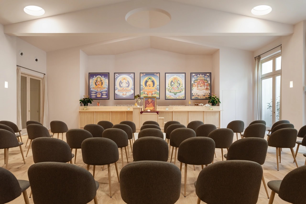 Vista frontal de la sala de meditación del centro Kadampa de Barcelona con las sillas en primer plano y el altar y las representaciones en segundo plano.