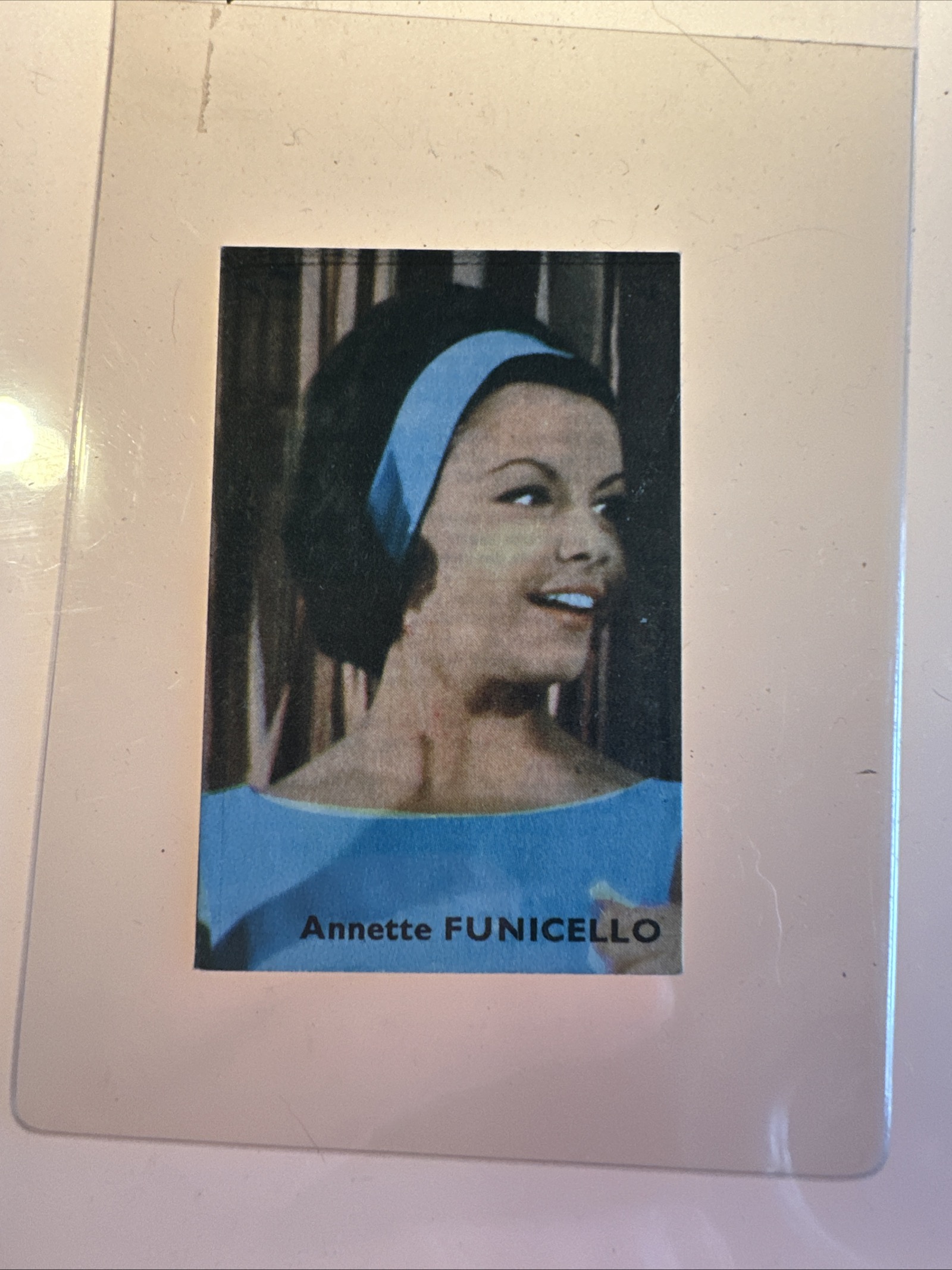 Mid-1960s Annette Funicello trading card showing color portrait in blue dress and headband, standard 2.5 by 3.5 inch format in clear plastic protector